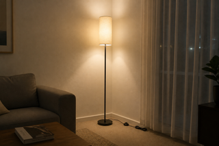 Corner floor lamps NZ — Chandelle linen column floor lamp glowing in the corner of a New Zealand lounge at night, warm light washing both corner walls under a 2.4m ceiling