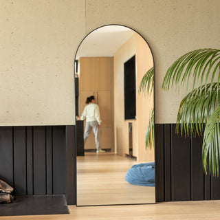 A freestanding full length arched mirror leaning against a wall in a styled New Zealand bedroom