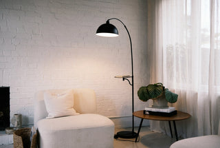 Black floor lamp NZ — the matte black Nero Tray lamp beside a boucle reading chair in a warm Kiwi lounge at dusk