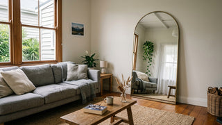 NZ living room with arched full length mirror leaning against the wall beside sofa — living room mirror placement NZ