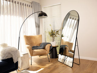Titan Arched Full-Length Freestanding Mirror in a living room beside a stylish single couch