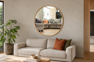 Decorative wall mirror NZ — Aure round oak-framed wall mirror above a linen sofa in a warm modern Kiwi lounge