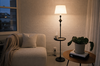 Floor lamp NZ rental — slim black floor lamp with built in side tray glowing warm in a small Auckland flat lounge corner, no drilling required