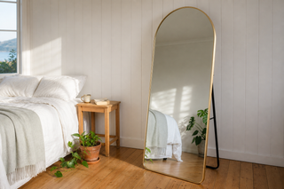 Gold arch mirror NZ, slim gold full length arch mirror leaning in a New Zealand weatherboard bedroom