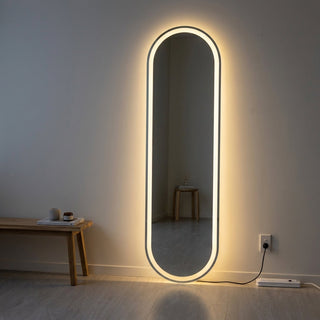 LED vs standard full-length mirror NZ — Lyra Oval LED frameless oval mirror glowing warm in a dim dressing corner