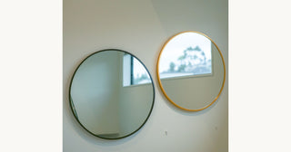 Two round wall mirrors mounted on wall in NZ home showing gold and black frame options