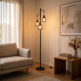 Black floor lamps by C&F Creation: the Voltaire three light cage lamp glowing beside a sofa