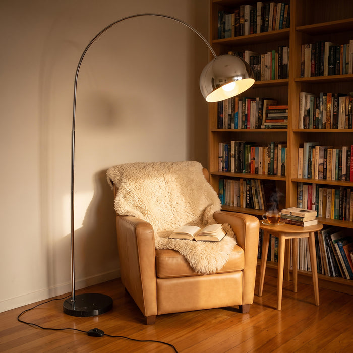 Cosmo Chrome Marble Base Floor Lamp curving over an armchair to light a quiet reading corner