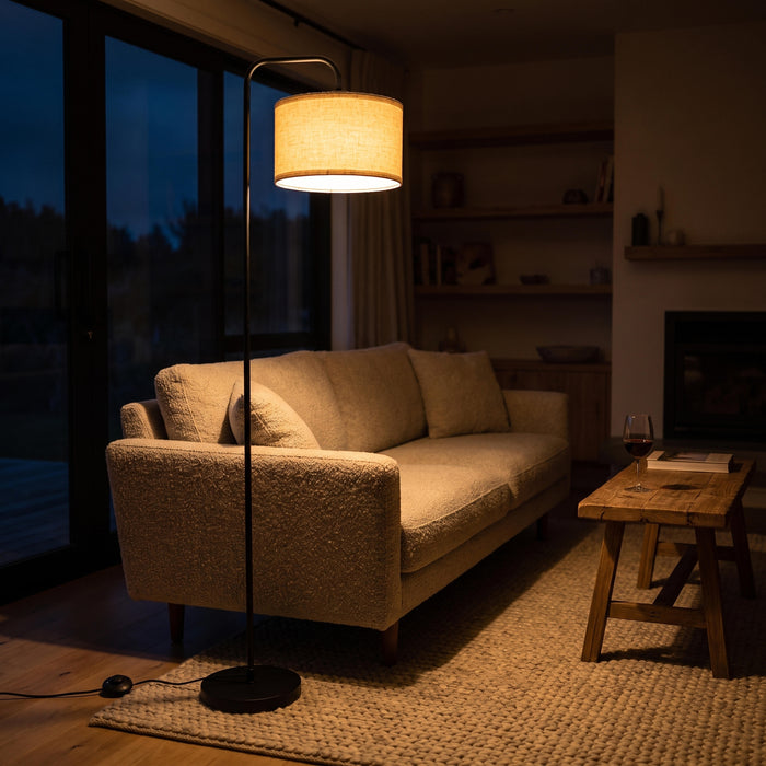 Marceau Linen Drum Floor Lamp switched on in the evening, filling a darkened room with warm light