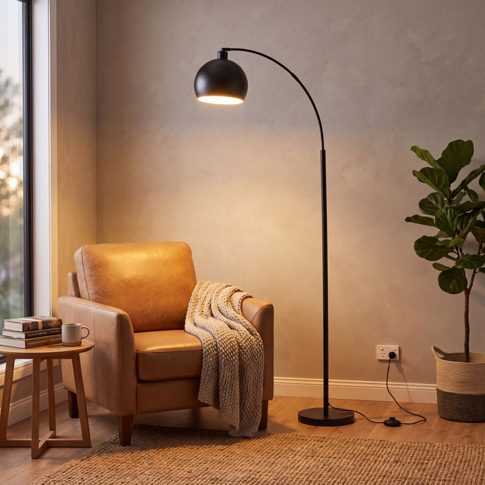 Saturne Black Globe Arc Floor Lamp lighting a reading corner beside a leather armchair