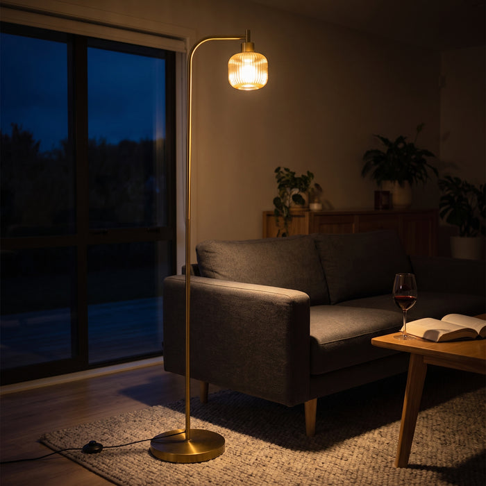 Solara Fluted Lantern Floor Lamp switched on at night, its fluted amber glass shade glowing in a dark evening living space