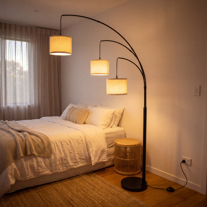 Trilogy 3-Light Floor Lamp casting a soft glow beside a bed in a calm bedroom