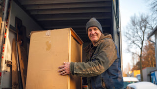 A delivery worker carefully unloading a large full-length mirror from a moving truck, representing premium delivery service with expert handling of fragile items.